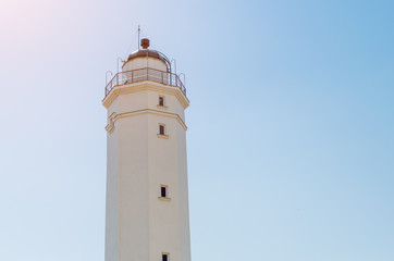 Fototapeta na wymiar White lighthouse against the blue sky on a sunny day