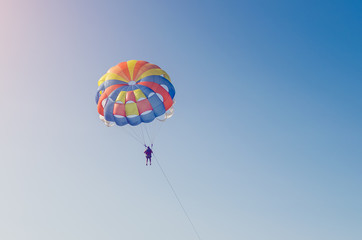 A man flying on a parachute over the sea with a boat
