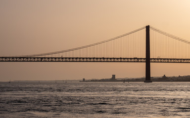 Ponte 25 de Abril, River Tagus, Portugal. A backlit dusk view of the iconic Lisbon suspension bridge over the River Tagus between Lisbon and Almeida.