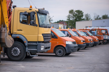 Multiple cars, trucks, loaders, concrete mixers and construction machinery in large parking lot in...