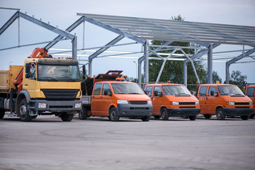 Multiple cars, trucks, loaders, concrete mixers and construction machinery in large parking lot in...