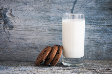 Chocolate chip cookies, milk, rustic wood background