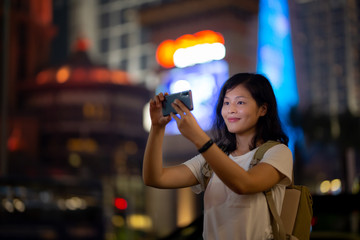 Young woman use smartphone on Macau street at night