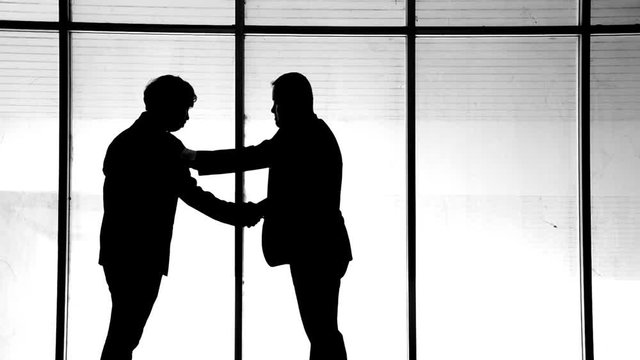 Silhouette: businessmen shake hands to join the business