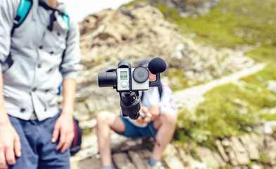 Blogger holding camera on monopod in mountains