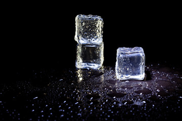 ice cubes reflection on black table background.