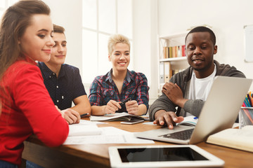 Group of diverse students studying at wooden table