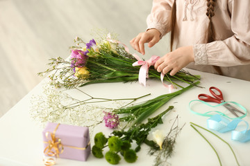 Little girl preparing bouquet of flowers for mother at home