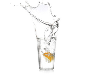 Glass with splashing water and sliced citrus fruit on white background