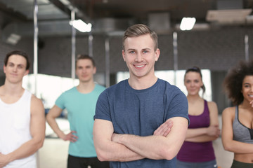 Fototapeta na wymiar Sporty man with group of athletes in gym