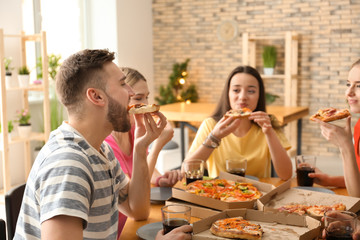 Young people eating pizza at table indoors