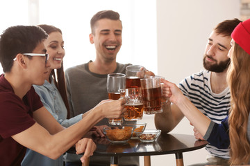 Group of friends clinking glasses with beer in bar
