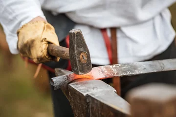 Foto op Plexiglas Blacksmith hammering a piece of steel © Dziurek