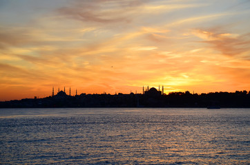 Naklejka premium Sunset.Silhouettes of Sultan Ahmed Mosque (Blue Mosque) and Hagia Sophia (Ayasofya) Mosque. View from sea of Marmara. Beautiful colorful sky. Istanbul, Turkey.