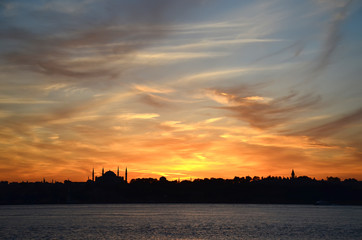 Naklejka premium Sunset.Silhouettes of Sultan Ahmed Mosque (Blue Mosque) and Hagia Sophia (Ayasofya) Mosque. View from sea of Marmara. Beautiful colorful sky. Istanbul, Turkey.