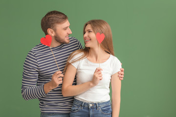 Happy young couple with red hearts on color background