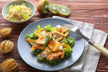 Plate with tasty chicken salad on wooden table