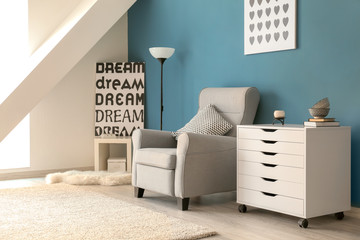 Stylish interior of living room with comfortable armchair and commode near color wall