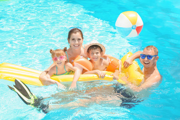 Happy family with inflatable mattress in swimming pool