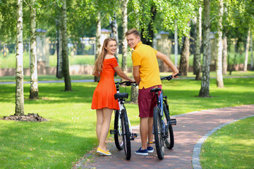 Young couple with bicycles walking in park