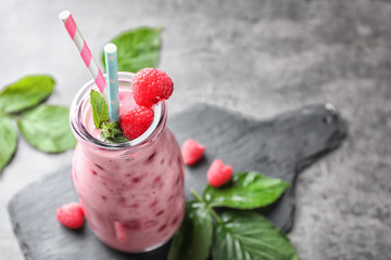 Glass bottle with tasty raspberry smoothie on light table