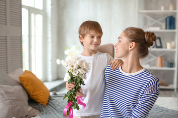 Mother receiving flowers from her cute little son at home