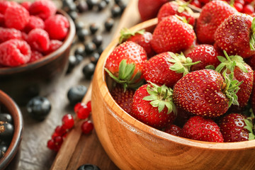 Bowl with ripe strawberries on wooden board