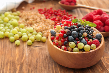 Bowl with fresh ripe berries on wooden table