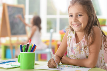 Portrait of a cute schoolgirl sitting at table