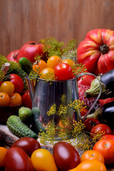 Cherry tomatoes in a metallic jug surrounded by different vegetables