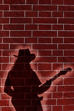 Shadow of musician whit guitar on brick wall 
