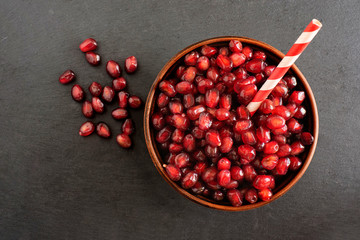 Pomegranate seeds in a bowl on a dark background