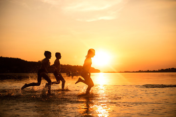 Happy children playing on the beach at the sunset time