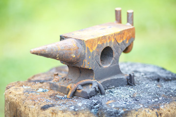 Old rusty rugged anvil on wooden table
