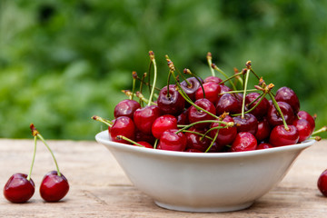Bowl with fresh cherry on rustic wooden table outdoor