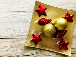 christmas decorations in red and gold over gold tray on wooden table