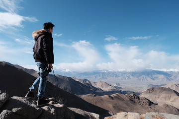 young traveler men with canera at top of the mountain a breathtaking landscape Leh, Ladakh, North India, wanderlust travel concept, space for text, atmospheric epic moment