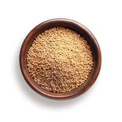 mustard seeds in a wooden bowl, isolated on white