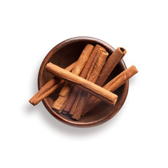 cinnamon sticks in a wooden bowl, isolated on white