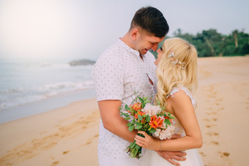 newlyweds standing and hugging on tropical beach