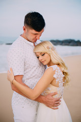 newlyweds standing and hugging on tropical beach