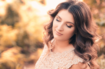 Fototapeta premium Beautiful woman with long curly hair over nature background. Autumn portrait. 20s.