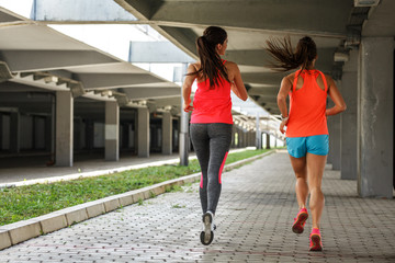 Obraz premium Two female runners jogging around the city.Urban workout concept.Rear view.