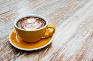 Cappuccino coffee in yellow cup lay on wooden table,Relax time with coffee,Art of coffee