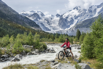 Senior woman, riding her e-mountain bike on the trail to the Morteratsch glacier near Pontresina ,...