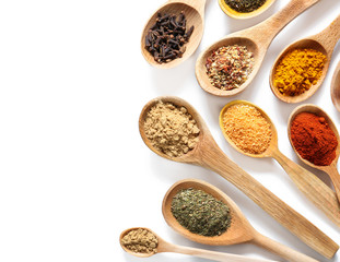 Wooden spoons with different spices on white background