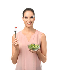 Young woman with fresh vegetable salad on white background