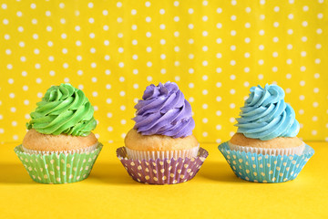 Delicious birthday cupcakes on color background