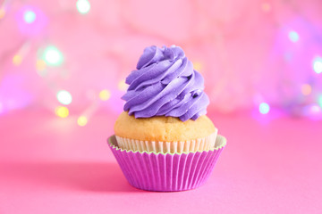 Delicious birthday cupcake against blurred lights