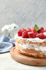 Delicious cake with strawberries on wooden board